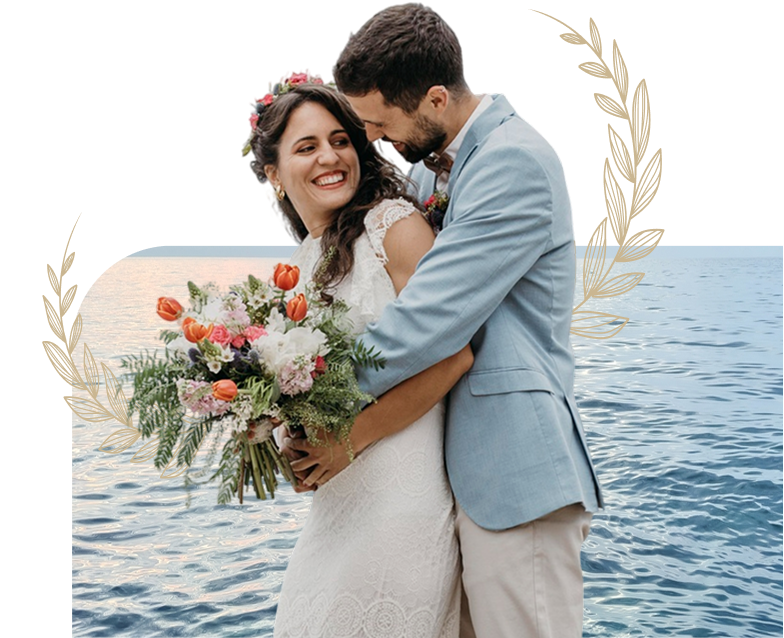A couple embracing with a bridal bouquet at a seaside wedding